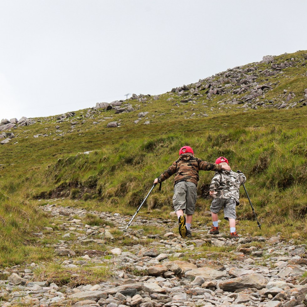 Older brother helps his sibling up the hill