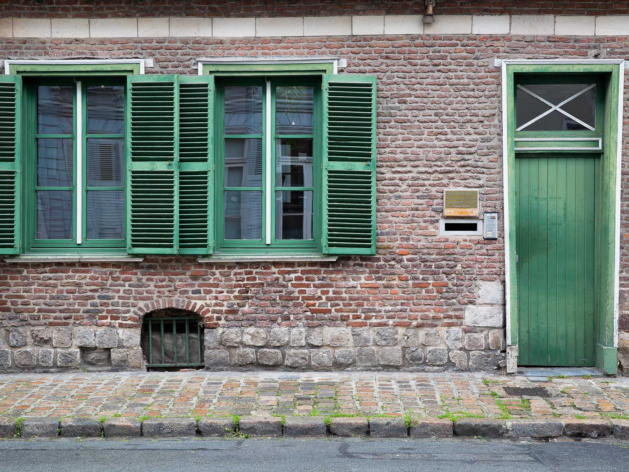 Green shutters and door on red brick in Lille, France