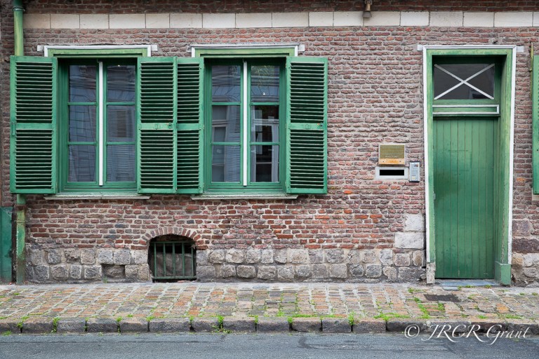 Green shutters and door adorn a red brick house in the old quarter of Lille, France