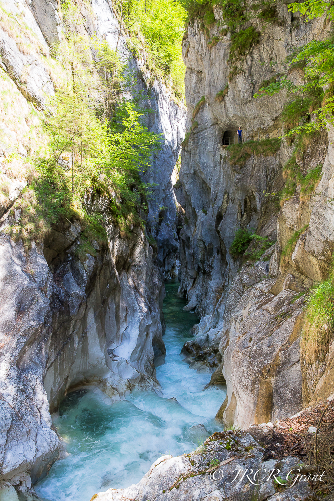 An adult stands on the Kaiserklamm path, high above the river in the gorge below, lending scale to this geographical formation.