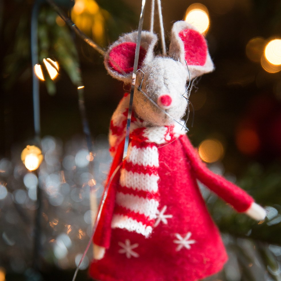 A knitted mouse ornament on a Christmas tree
