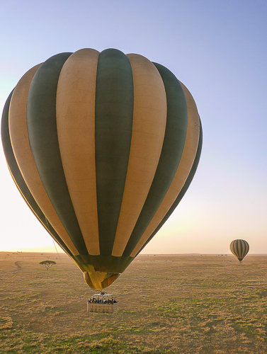 The basket of a hot air balloon with eager tourists looking down on the plain below.