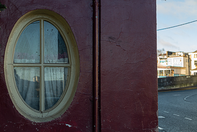 The dull oval window of an old bar besides the River Lee on George's Quay, Cork City