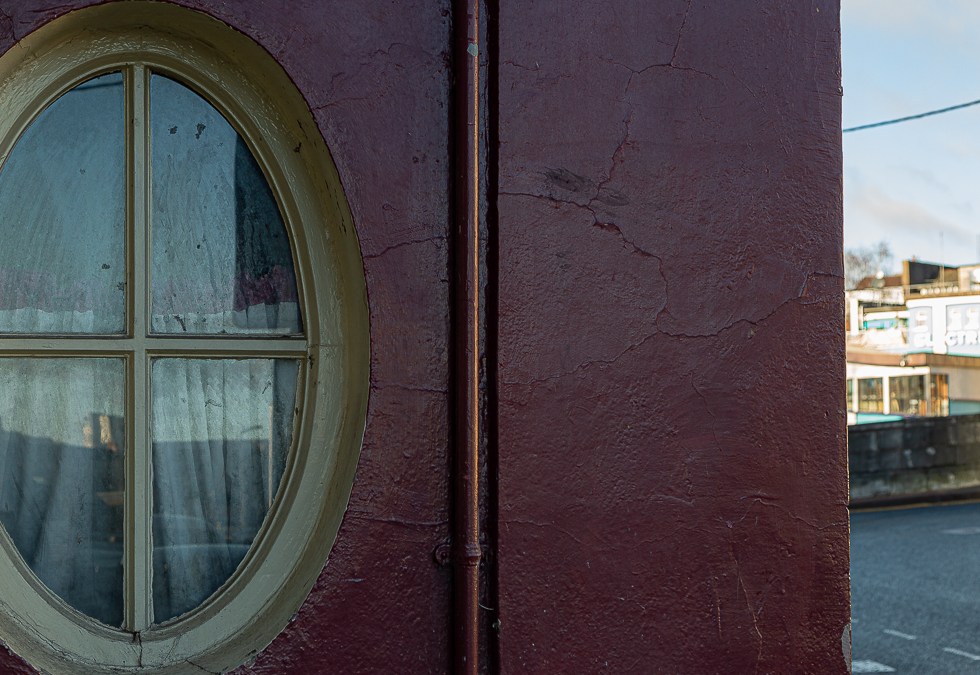 Cream oval window with a half curtain, but nothing going on inside