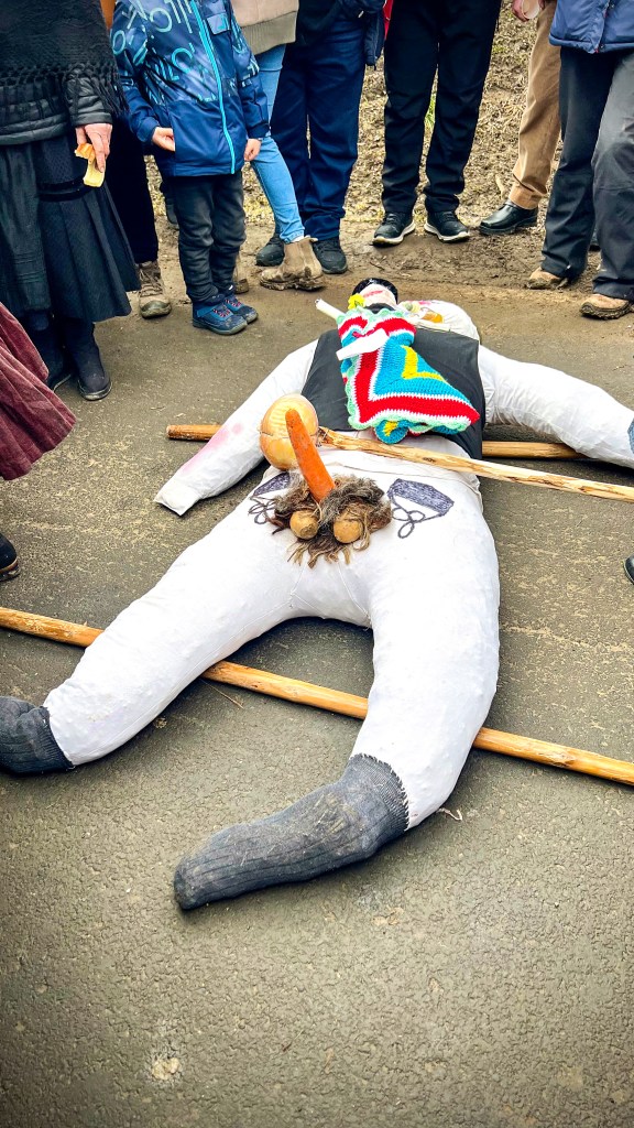 An effigy dressed as a snowman lies 'dead' on the floor, signalling the end of winter